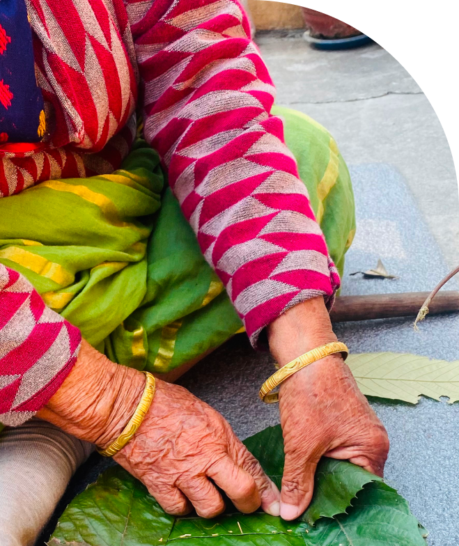 Nepali woman learning to craft a bowl from a leaf.